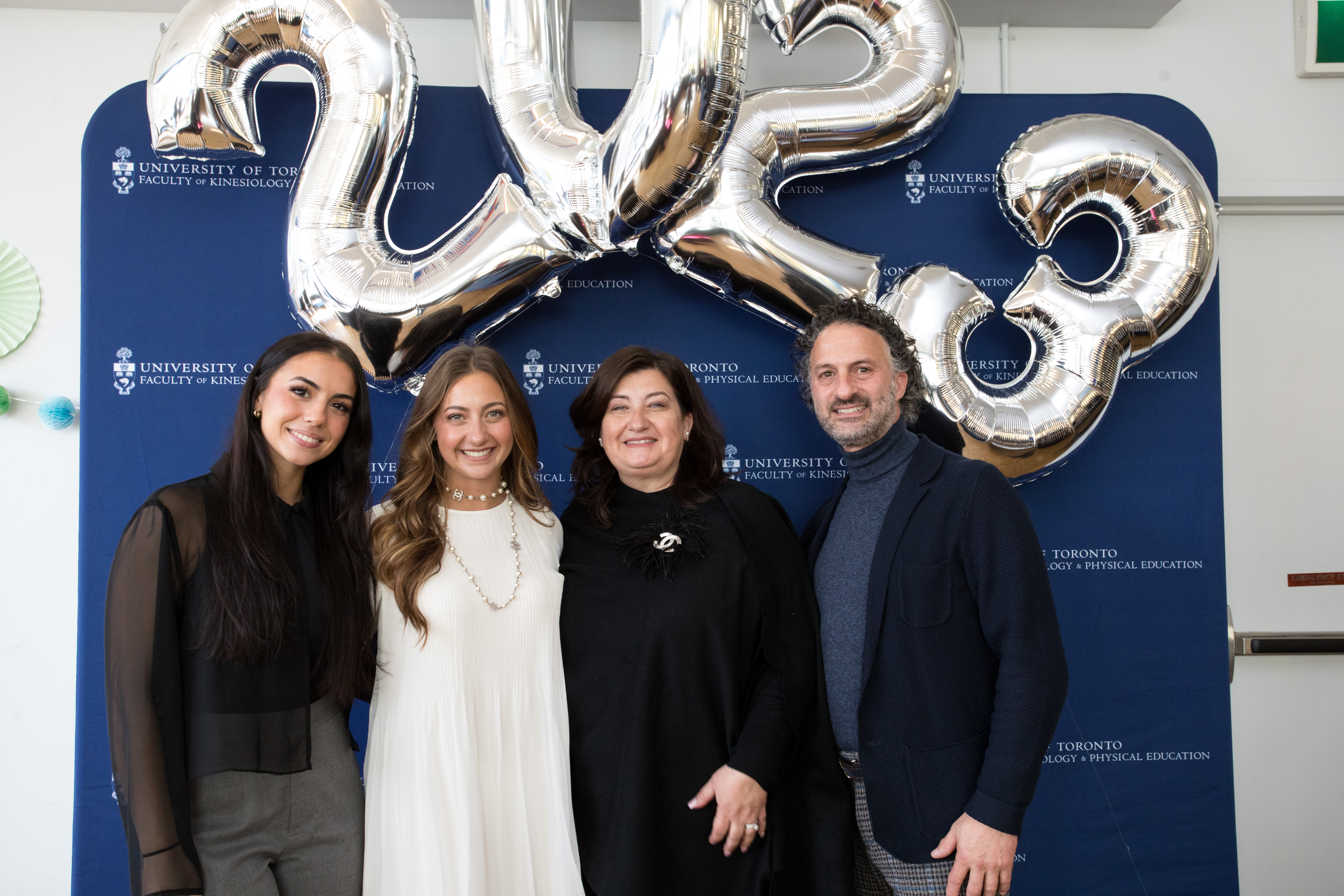 Francesca Tatangelo with family in front of faculty backdrop and balloons