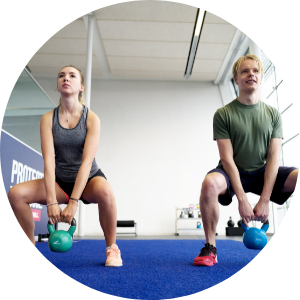 two students squatting kettlebells