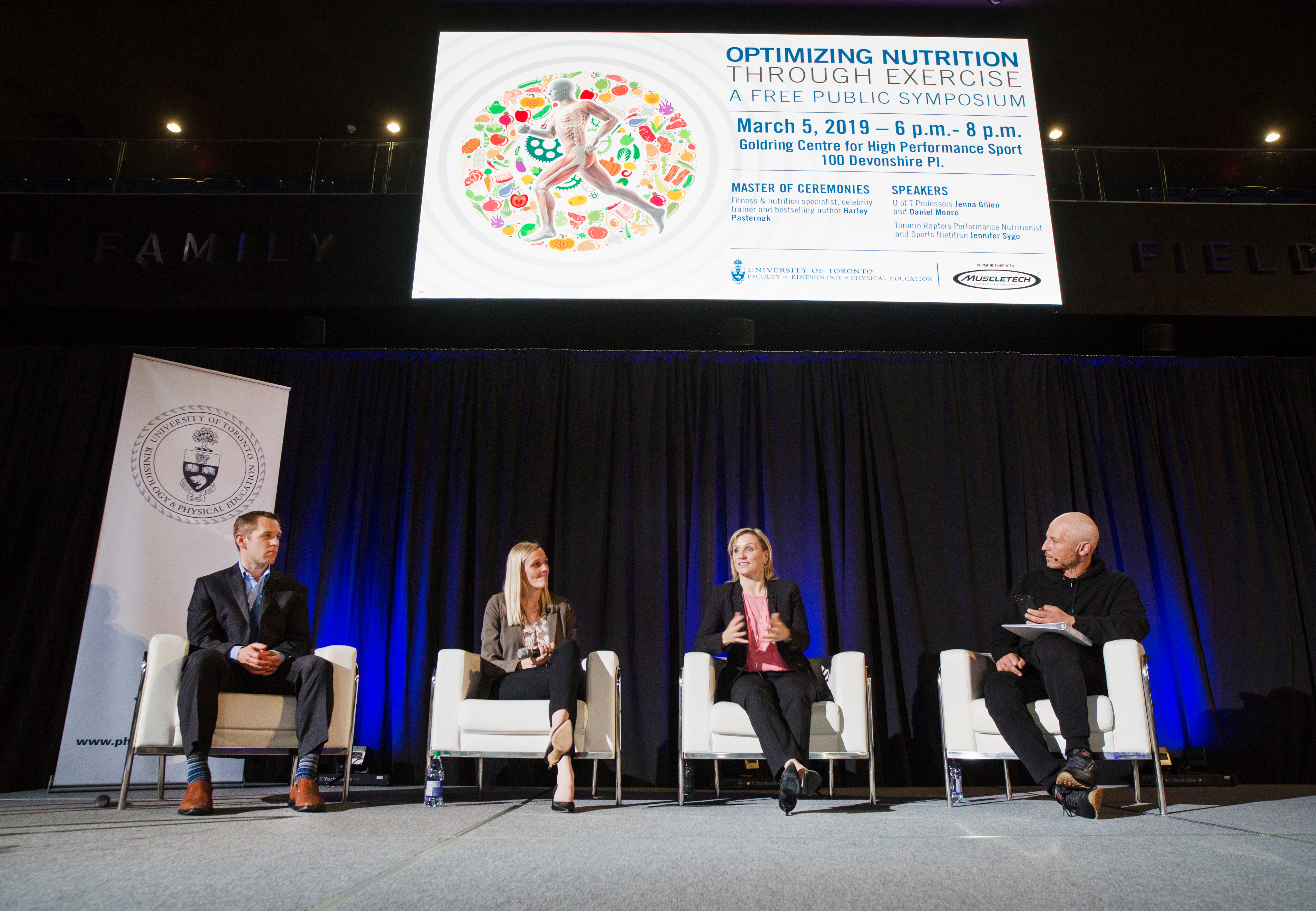 Group of 4 people on stage in discussion at symposium