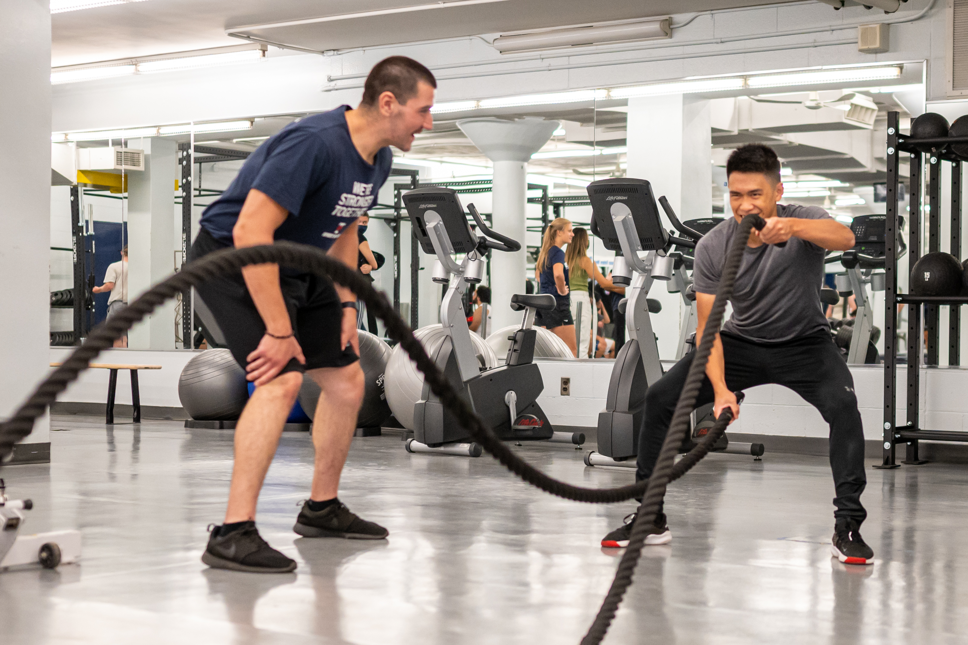 coach training student using battle ropes