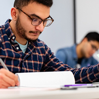 south asian male student writing on paper