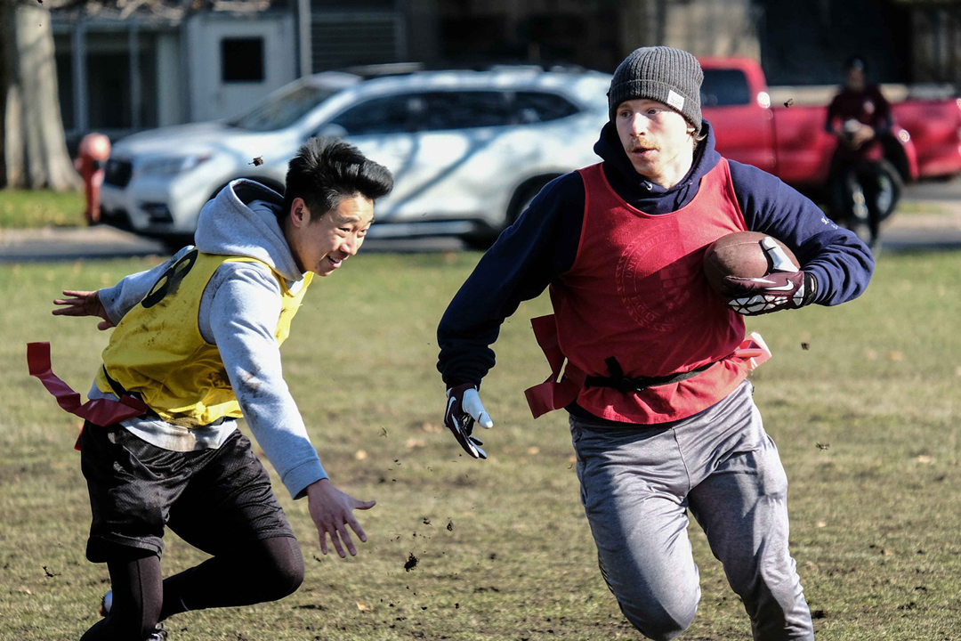 guys running playing football on a field