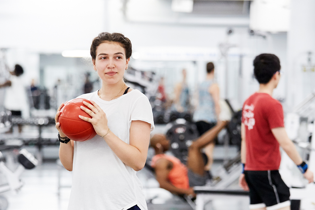 girl holding medicine ball in gym