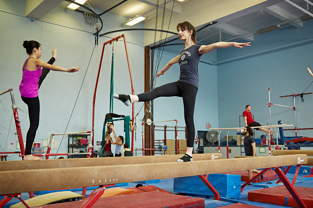 girl balancing on one leg on the balance beam