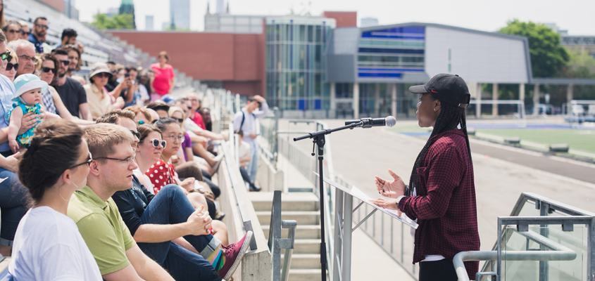 Female student at podium addressing crowd