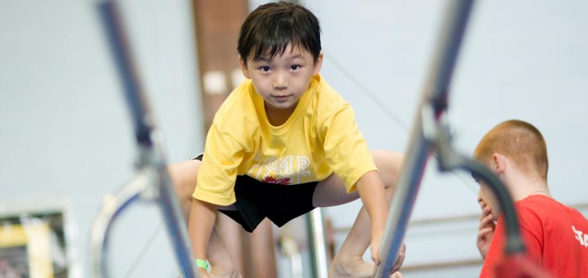 young boy balancing on parellel bars