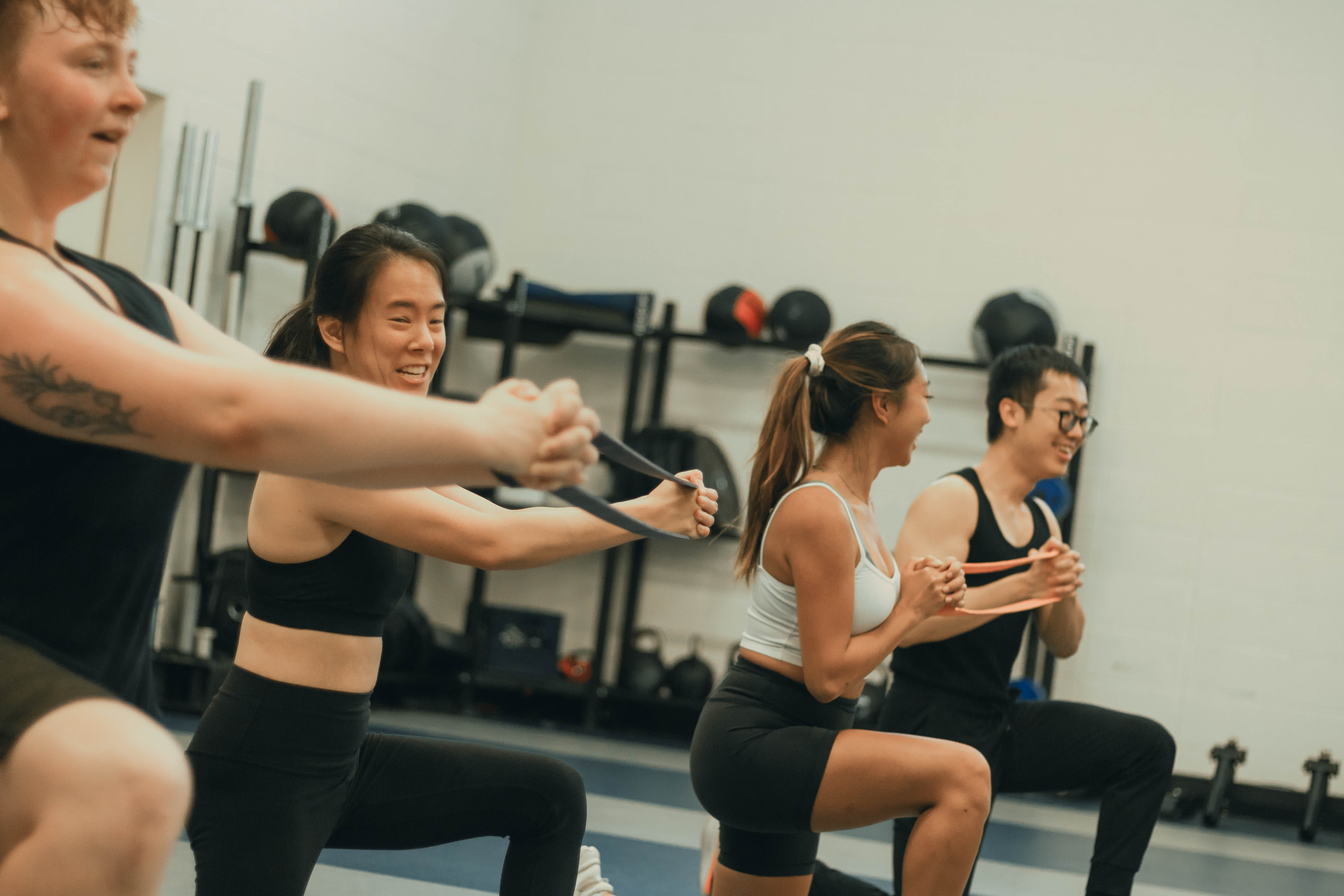 Group of students in a kneeling lunge positioning smiling while working out