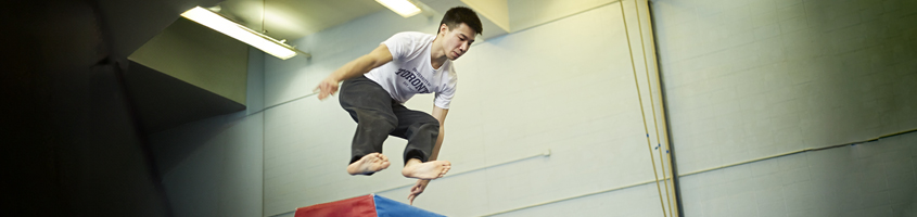 Man jumping on top of a platform, wearing a U of T t-shirt