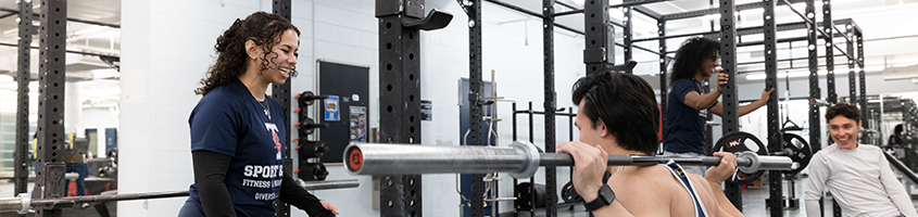 Woman coaching man doing a barbell squat