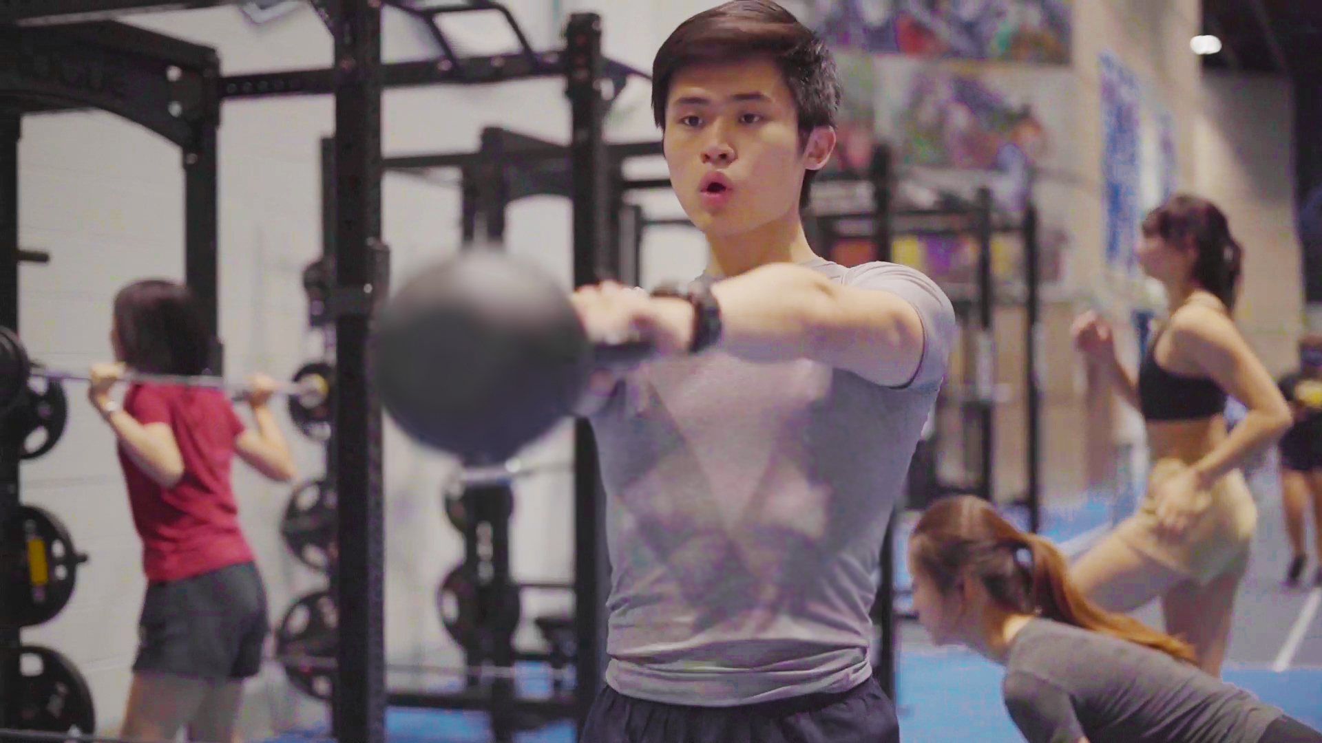 Student group fitness participant swinging kettle bell