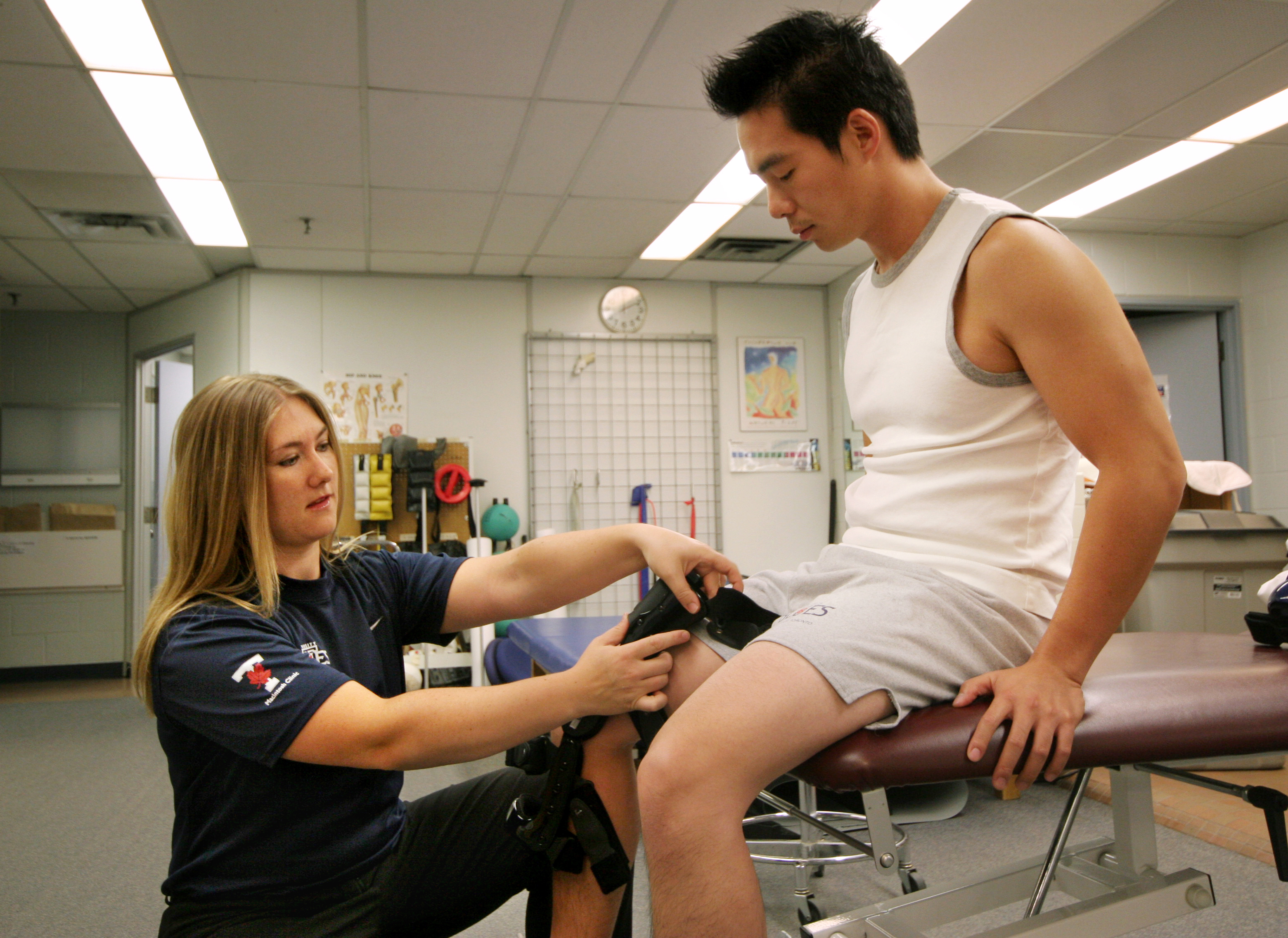 Therapist assists patient with knee brace and treatment in clinic