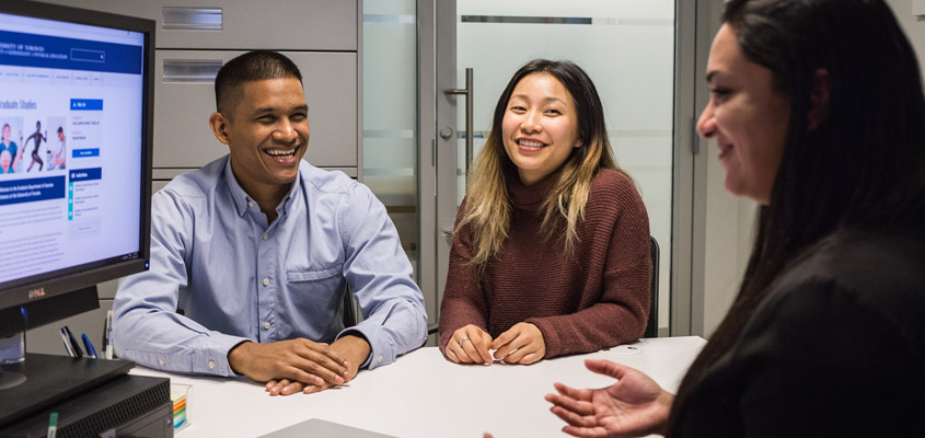 Staff member providing academic advice to graduate students in an office