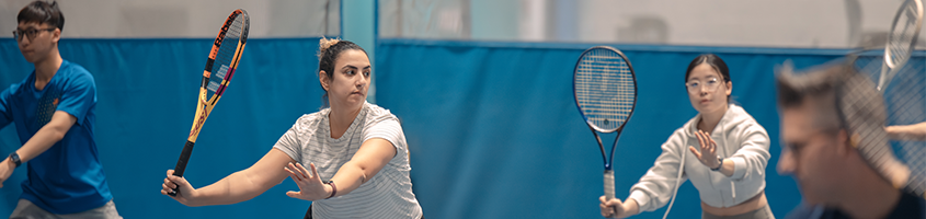 Two women playing tennis with a blue background