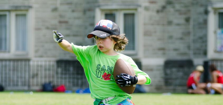 A young boy runs with a football