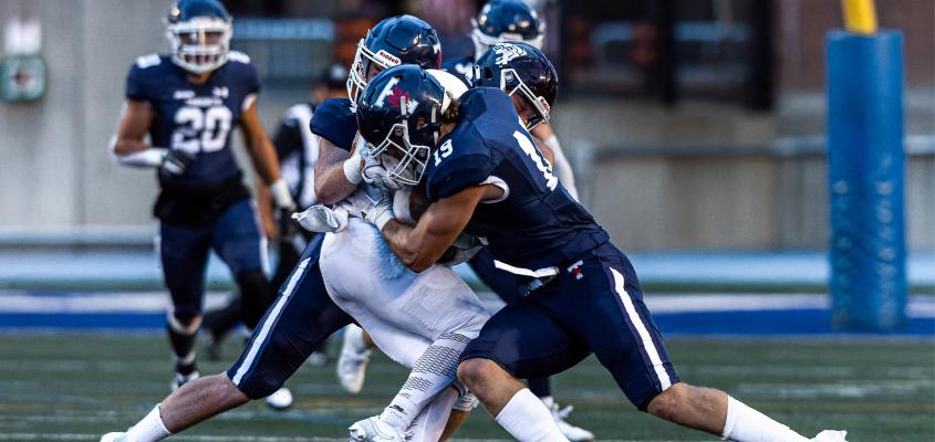 Ryan Collins tackles an opposing football player as a Varsity Blue