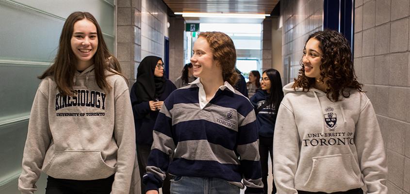 Three student ambassadors walking donw a hallway at the Athletic Centre