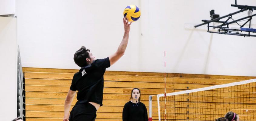 Volleyball player jumping while throwing ball.
