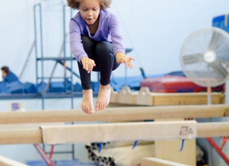 A girl jumping on a balance beam