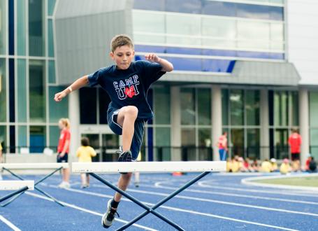 A young boy jumping over a hurdle