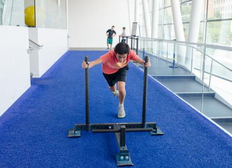 A teenager pushing a training sled