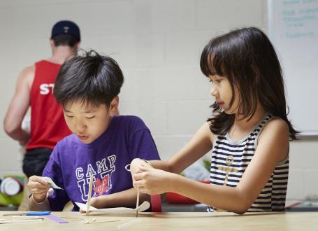 Campers work on a project with various materials