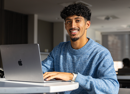 Shan Dhanoa studying on his laptop on campus. 